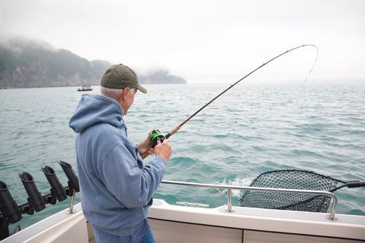 A senior man catches a salmon while fishing in Alaska